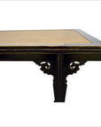 Close-up of dark wood Chinese rattan coffee table corner with carved details and light rattan tabletop.