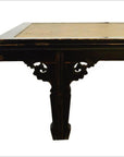 Close-up of a light rattan coffee table with black carved bracket, tabletop inset visible.