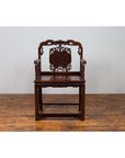 Dark rosewood Chinese chair with hand-carved backrest, 19th century, on wooden floor against plain wall.