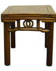 Brown wooden square side table with rounded legs and carved friezes under the seat, close-up view.