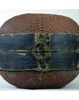 Close-up of a Chinese storage basket made of woven rattan with a black wooden band and metal ring clasp, plain background.