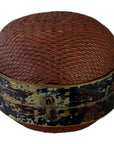 Close-up of round brown rattan Chinese storage basket with domed lid, black weathered floral band, and small lock.
