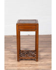 Brown elmwood lamp table with single drawer and cracked ice shelf, tall and narrow design, indoor setting.
