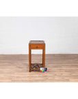 Brown elmwood lamp table with single drawer and cracked ice shelf on wood floor indoors.