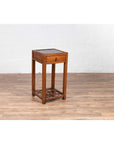 Brown elmwood lamp table with single drawer and cracked ice shelf on wooden floor near a white brick wall indoors.