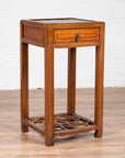 Brown elmwood lamp table with single drawer and cracked ice shelf, four legs, on wooden floor indoors.