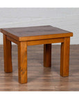 Natural wood Chinese vintage side table with thick legs on wooden floor, white brick wall background.