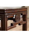 Close-up of dark wood side table with carved medallions and smooth corner, vintage Qing style.
