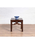 Dark wood side table with carved medallions and dark patina, blue and white bowl on top, indoor setting.