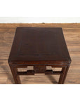 Dark wood Chinese vintage Qing style side table with carved medallions, set on wooden floor by a white wall indoors.