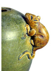 Close-up of a greenish ceramic Chinese Water Dropper missing its top, with a small brown mouse figurine clinging to it.