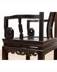 Close-up of a dark wood Chinese wedding chair with curvy pierced splat and serpentine arms.