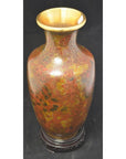 Red and gold cloisonné vase with a wide gold rim and floral pattern, on a dark round base. Close-up view.