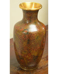 Close-up of a red and gold cloisonné vase with floral patterns on a wooden surface.