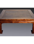 Brown lacquered coffee table with curved legs, set against a neutral gradient background.