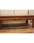Brown wood coffee table with openwork aprons, two drawers, carved legs, and horse hoof feet on wooden floor.