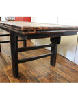Brown woven rattan coffee table on wooden floor in room with white and red walls.
