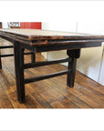 Brown woven rattan coffee table on wooden floor in room with white and red walls.
