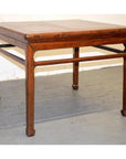 Wood coffee or side table with straight legs and decorative apron on gray floor against a white wall.