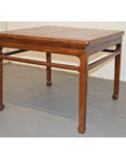 Square wooden coffee or side table with straight legs, minimalist design, on a gray floor.