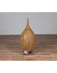 Mustard yellow ceramic vase with tapered spout on wooden floor, color card in front.