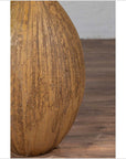 Mustard yellow ceramic vase with tapered spout on wooden floor against white wall, handmade Thai style.