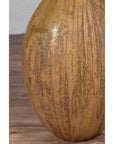Close-up of mustard ceramic vase with tapered spout on wooden floor.