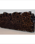 Close-up of copper batik ink block with intricate floral and leaf patterns, used for garment making.