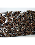 Close-up of copper Batik ink block with intricate floral carvings, used for garment making.