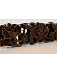 Close-up of a copper Batik ink block with carved black and gold floral patterns in an antique style.