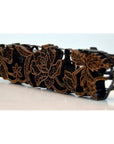 Close-up of a copper hair clip with batik ink block style and intricate gold floral patterns on a white surface.