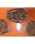 Copper Batik ink blocks with intricate floral designs for garment making on wooden surface, close-up view.
