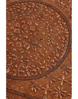 Close-up of copper coffee table surface with embossed intricate floral and geometric patterns.