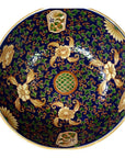 Close-up of blue, green, and gold floral patterned Ming porcelain bowl with central circular design.