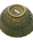 Green celadon porcelain bowl upside down, showing base sticker and crackle glaze on white background.