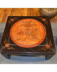 Square wooden Kang table with orange painted central motif and horse hoof feet, close-up.