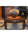 Large ceramic vase on decorated Kang table, with birdcages and dark wooden furniture in the background.