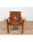 Brown wooden plantation lounge chair with curved slatted seat, color card on seat, on wood floor indoors.