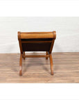 Brown wooden lounge chair with curved seat and slatted back, rear view on wooden floor indoors.