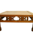 Light brown elm wood coffee table with hand-carved designs and sturdy square legs on white background.
