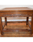 Brown elmwood stool or table with rattan inset top, carved scroll apron, and stretcher base on hardwood floor.