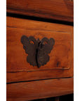 Close-up of dark wood fretwork and carved Chinese cabinet with ornate dark metal butterfly-shaped handle and keyhole.