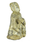 Close-up of glazed terracotta fertility doll, seated figure with child, light material and dark accents.
