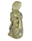 Brown glazed terracotta fertility doll with faded patterns, seated holding a small figure in its lap, close-up.