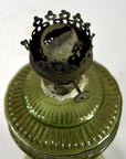 Close-up of a green glass oil lamp with decorative metal burner and exposed wick, in very good condition.