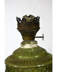 Close-up of green glass oil lamp with metal burner and worn, crown-shaped top, in very good condition.