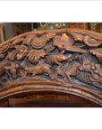 Brown wood arch sculpture with hand carved animals, flowers, and foliage in intricate decorative design.