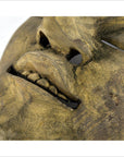 Close-up of brown wood hand-carved Balinese theater mask, showing detailed lips, teeth, nose, and visible wood grain.