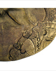 Close-up of a golden-brown hand carved Balinese theater mask with swirling patterns, wood texture visible.