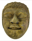 Brown wood Balinese theater mask close-up, hand carved with serene smiling face, closed eyes, and textured hair.